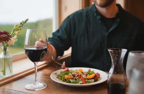 A man eating a salad at a windowside table.