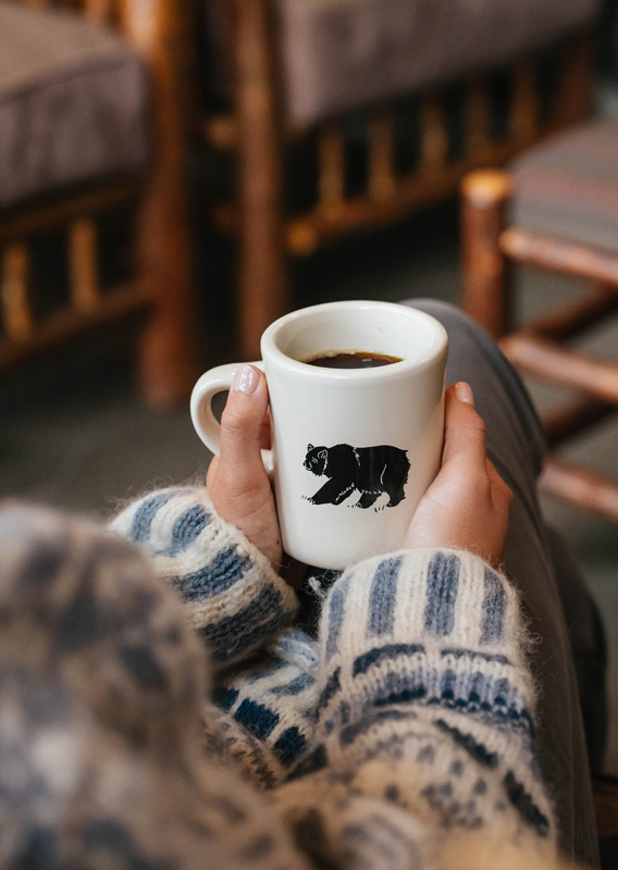 A person in a sweater holding a coffee cup
