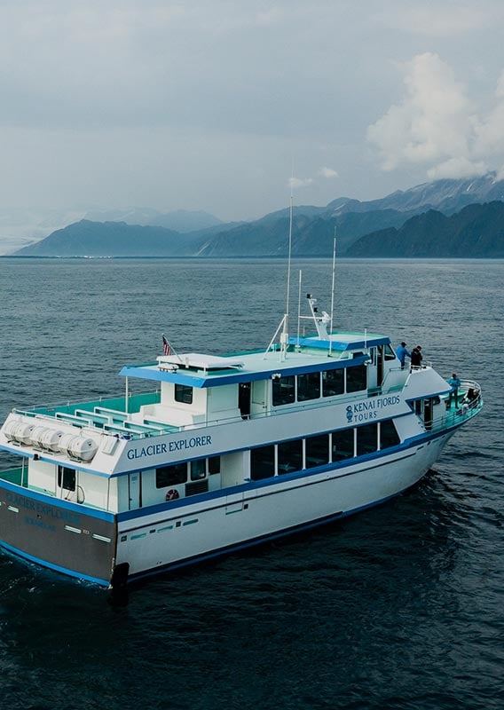 A boat cruises along the ocean near mountains.