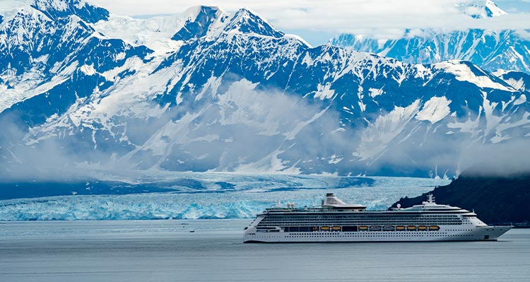 A large cruise ship near mountains and a tidewater glacier.