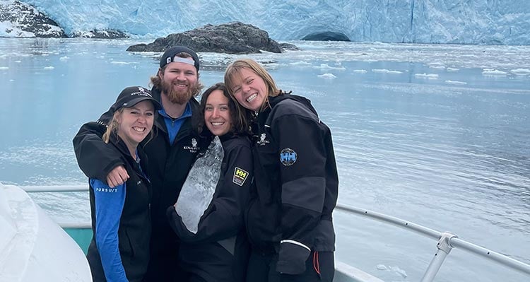 A group of tour guides stand on the deck of a boat.