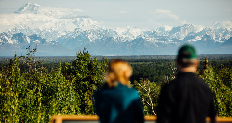 Two people standing at a viewpoint, looking at the mountain view.