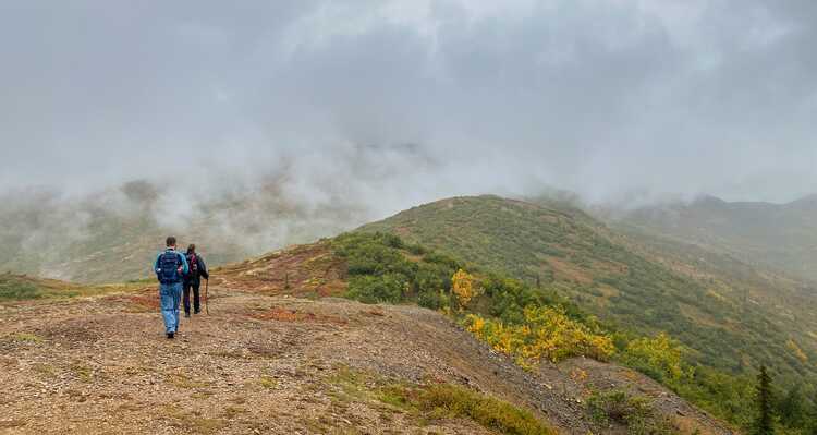 Two people walking across top of foggy mountain