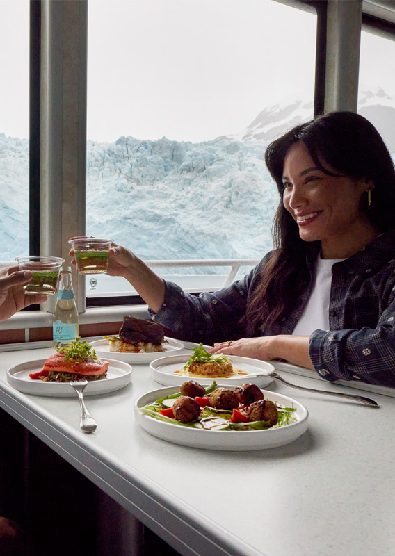 A couple dining on a KFT boat tour that's sailing beside Holgate Glacier