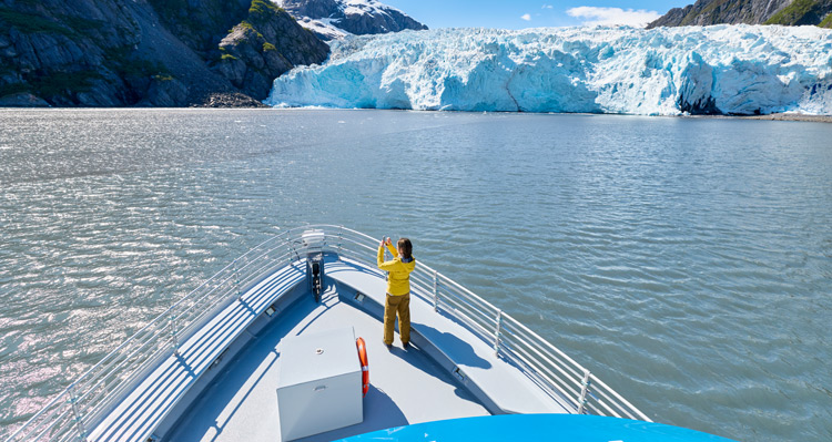 Person standing on bow of boat photographing Holgate Glacier.