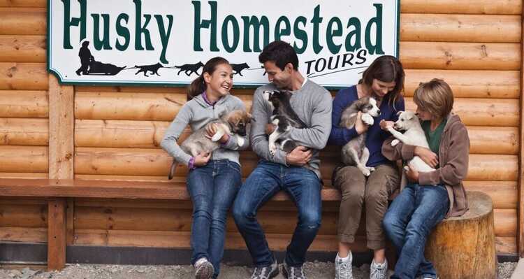 A family holding husky puppies at Husky Homestead