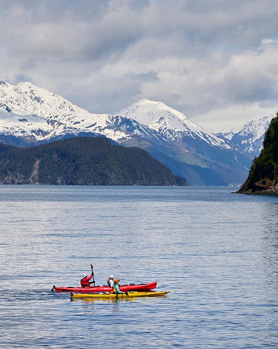 Two people walk out from a sauna onto a rocky beach.