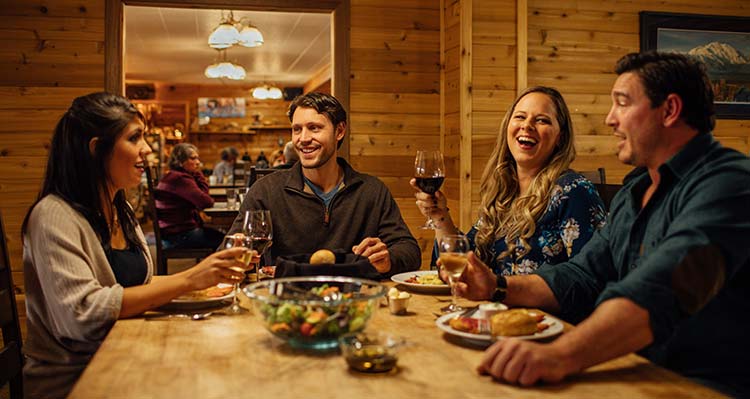 A group of friends dine inside a wooden cabin.