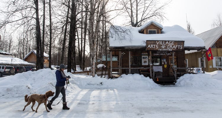 A person walking their dog outside of Village Arts-n-Crafts
